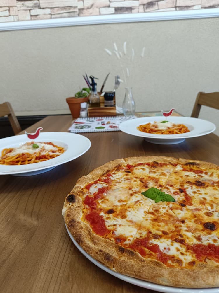 Margherita pizza és két tányér pasta az asztalon