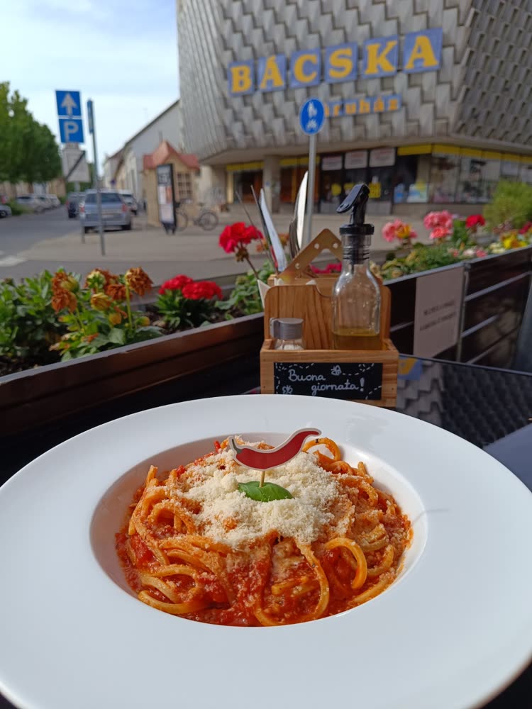 Csípős paradicsomos pasta közelről, háttérben a bajai utcakép